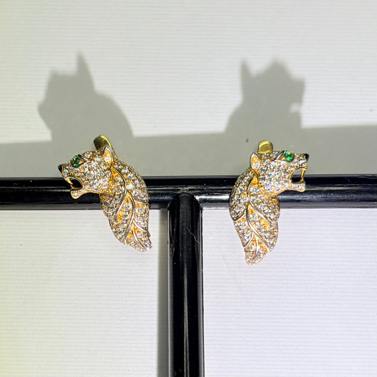Original photo of gold-tone feline earrings with green accents